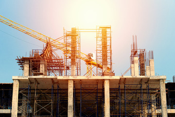 Fototapeta na wymiar Construction site with steel scaffolding,shallow depth of field..Concrete foundation of high rise building with yellow tower crane at sunset,no worker low angle view.