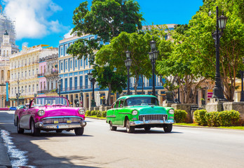 Pinker amerikanischer Cabriolet Oldtimer und grüner Oldtimer fahren auf der Hauptstrasse in Havanna Stadt Kuba - Serie Kuba Reportage - obrazy, fototapety, plakaty