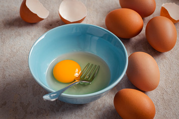 Raw broken egg with yolk in bowl .