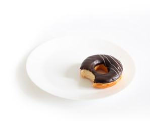 Eaten chocolate donut isolated on white background. doughnut has been bitten on a white plate