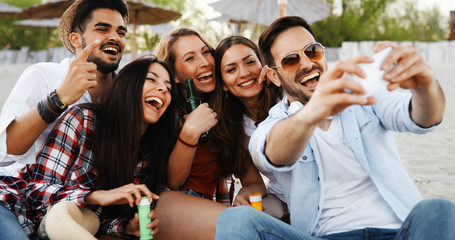 Group of young friends laughing and drinking beer