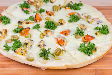 Cooked pizza with mussels on bamboo cutting board close-up