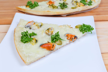 Slice of cooked pizza with mussels on the square dish