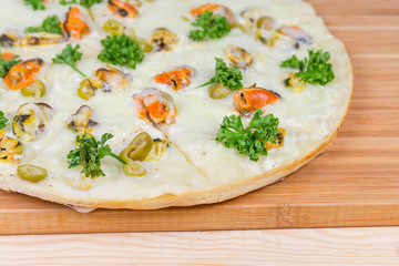 Part of cooked pizza with mussels on cutting board closeup
