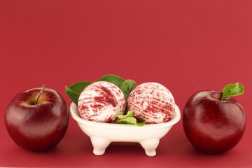Bath bombs set with apple extract. Bath bombs and ripe red apples set on a red  background.Beauty and health concept.