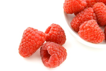fresh red raspberry fruits in a small white bowl