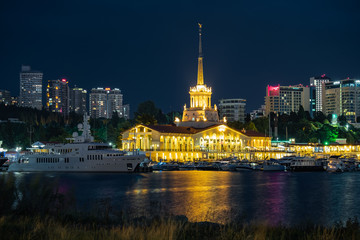 Obraz premium Sochi sea port. Evening illumination of the building. Attraction of the resort city. Parking for yachts and ships. City view.