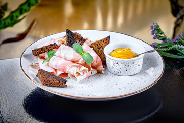 Chunks of salted bacon with rye bread and mustard. Unhealthy snack. Traditional ukraine cuisine. Salo or lard served with toast and mustard on white plate. Copy space. Food background. Front view