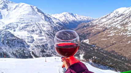 Close up of glass with red wine over landscape of caucasus mouintains in sunny day, Elbrus
