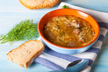 Homemade soup with noodles and meatballs on a wooden table. Traditional rural dinner