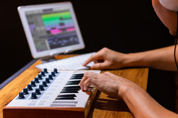 Fototapeta na wymiar male composer arranging music on midi keyboard and tablet computer in home studio