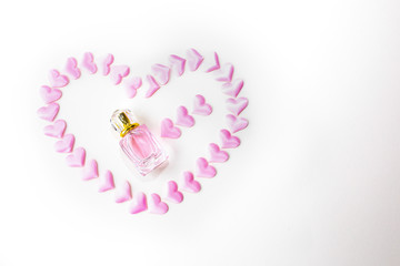Perfumes with pink hearts on white background. Simple minimalist flat lay. Present for mother's or woman's day. Romantic idea for Valentine's holiday. Postcard.