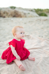 Beautiful little girl sitting on the beach