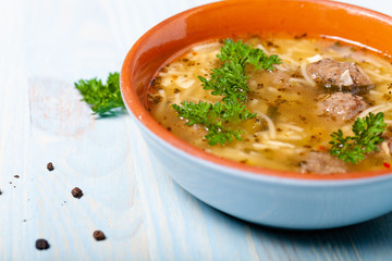 Homemade soup with noodles and meatballs on a wooden table. Traditional rural dinner