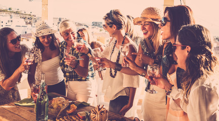 Fototapeta premium Group of nine people celebrate a birthday. Smiling women with red wineglass. wooden table, food and drink. Friendship concept