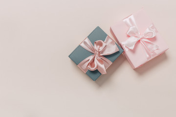 beautiful gift boxes wrapped in paper with gold and pink ribbon on a beige surface. Top view