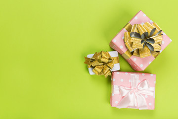 Gift box wrapped in pastel  paper with pink ribbon on green surface. Top view  with copy space.