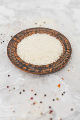 Raw white rice in wooden circular plat over concrete surface