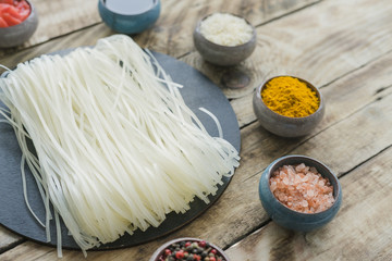 Close-up of homemade rice vermicelli and fresh ingredients over wooden bench