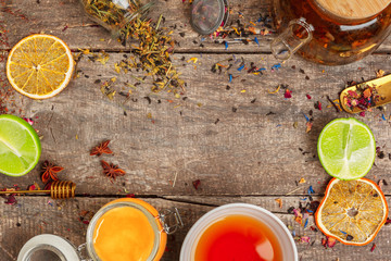 cups of healthy herbal tea with cinnamon, dried rose and camomile flowers in spoons over wooden...