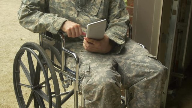military man in BDU in wheelchair with an touchpad