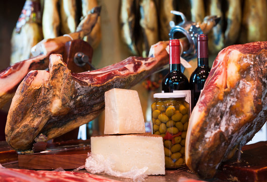 Still life of spanish pork jammon on holder, bottles of wine cheese and olives
