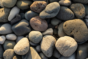 Fototapeta na wymiar various stones on the seashore with the warm sunset sun