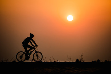 Obraz premium Silhouette man cycling on sunset background
