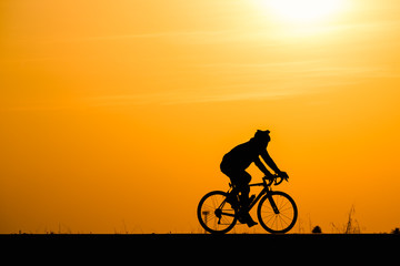 Naklejka na ściany i meble Silhouette man cycling on sunset background