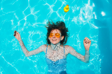 Redhead woman in blue swimming pool.