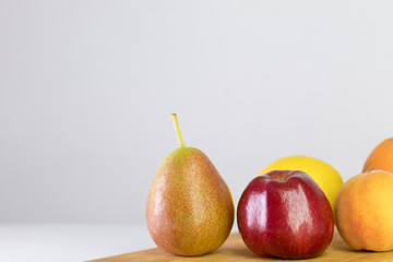 red apple, pear, lemon, orange, peach on white background, copy space