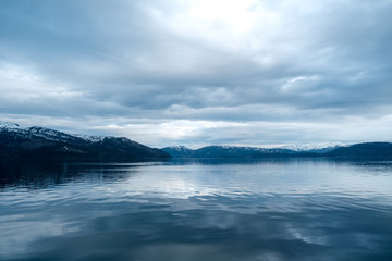 Man sitting on cliff edge alone enjoying aerial view backpacking lifestyle travel adventure outdoor vacations in Norway top of Reinebringen mountain.
