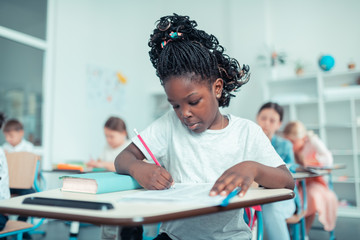 Schoolgirl doing sums with concentrated face at the test .