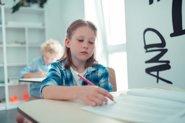 Naklejka na ściany i meble Tired school girl writing her maths test.