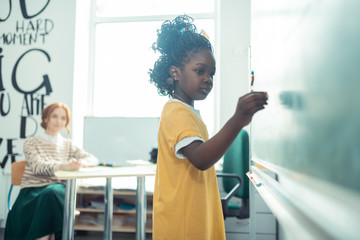 Thoughtful girl going to write on a blackboard.