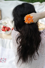 Obraz na płótnie Canvas Closeup of black haired woman with orange chrysanthemum bud in her hand