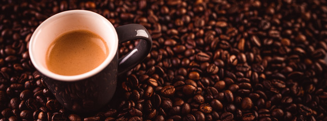 Brown espresso cup with coffee isolated on coffee beans.