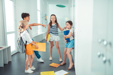 Rude children throwing papers of girl on the floor while bullying her