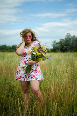 Happy girl on the field collects flowers