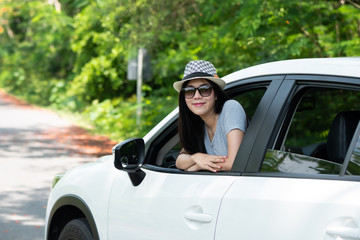 Happy asian women smile to summer holiday travel trip in the car on the road with sunlight, daylight and tree natural background. tourist vacation concept