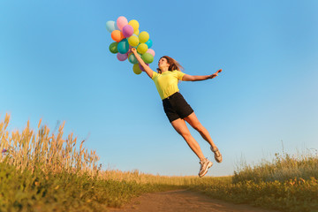 follow your dream, inspiration concept, young woman with colorful balloons jumping in summer field. fun, vacation, bright life
