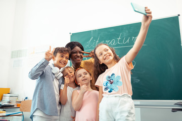 Teacher and children feeling happy while making selfie together