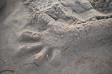 A positive handprint in the sand. A hand formed of sand.