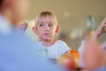 Cute blonde-haired schoolgirl having lunch with classmates