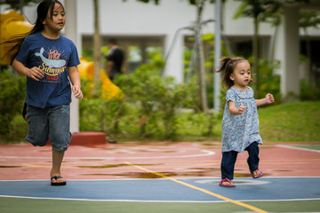 Asian girl playing with older sister in the park. 