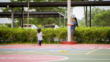 Asian girl playing with older sister in the park. 