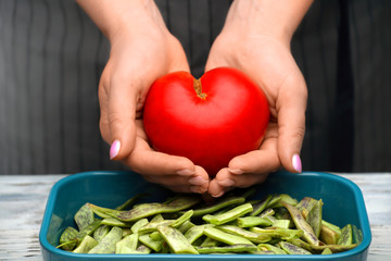 Tomato in the shape of a heart in female hands. Healthy food.