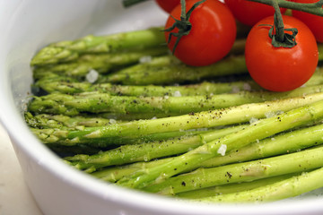 fresh vegetables asparagus and tomatoes in a white bowl