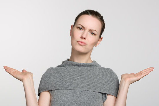 young woman in grey sweater makes a not know gesture with her arms