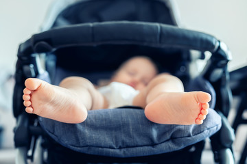 Cute adorable caucasian blond toddler bou sleeping in stroller at daytime. Children healthcare and...